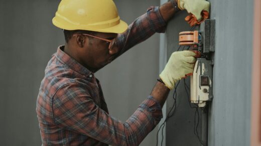 man in brown and white plaid dress shirt and yellow hard hat holding black and orange